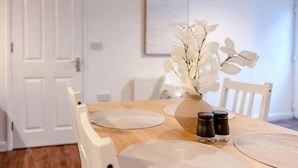 Una mesa de comedor con individuales, un jarrón con flores blancas y saleros y pimenteros.