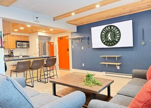 Een moderne woonkamer met een bank, een salontafel en een keuken in de achtergrond.
