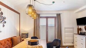 Ein modernes Zimmer mit Esstisch aus Holz, gepolsterten Sitzmöglichkeiten, einem Fernseher und einer Heizung.