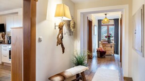 Ein Flur mit einer Bank, einer Lampe, einer Wanddekoration und einem Fenster mit Vorhängen.