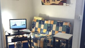 Una sala de estar con un sofá, una mesita, un televisor y un escritorio.