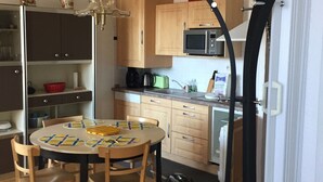 Una cocina compacta con armarios de madera, un microondas y una mesa de comedor con sillas.
