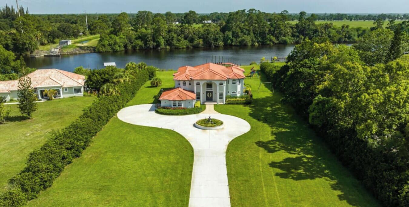 Una extensa propiedad con una casa central, un lago y un césped bien cuidado.