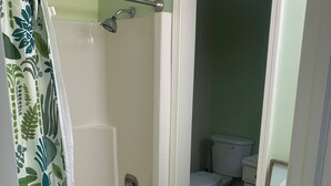 Et badeværelse med bruser, toilet og håndvask.