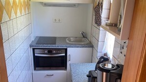 A compact kitchen with a built-in oven, a coffee maker, and a sink.