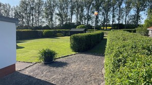 A well-maintained garden with a gravel path, neatly trimmed hedges, and a flagpole.