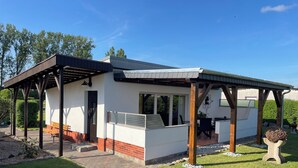 A modern house with a covered patio, a barbecue area, and a garden.