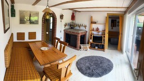 A cozy dining area with a wooden table and bench, a fireplace, and a large window.