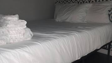A single bed with white bedding and a patterned headboard.