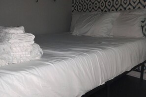 A single bed with white bedding and a patterned headboard. - The Tiny Nook in Downtown + Free Parking (Raleigh)