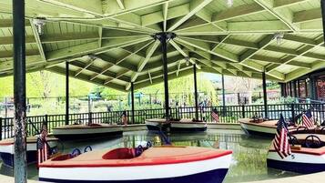 A covered boat rental area with multiple boats, some with American flags, and a pavilion structure.