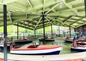 A covered boat rental area with multiple boats, some with American flags, and a pavilion structure. - The Tiny Nook in Downtown + Free Parking (Raleigh)