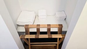 Une petite pièce étroite, avec un banc en bois et trois piles de serviettes blanches appuyées contre le mur.