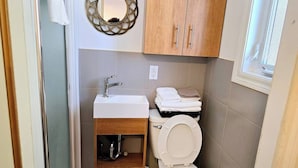 Une petite salle de bain avec un lavabo blanc, des toilettes et un miroir au-dessus du lavabo.