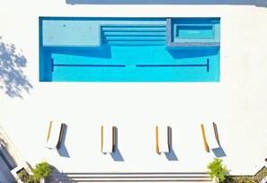 A top-down view of a swimming pool with a blue interior, surrounded by a white building. - Welcome to Casa Hibiscus, your private tropical escape in Miami! 4-bd, 4-baths (Miami)