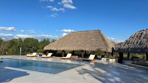 A pool area with lounge chairs and a thatched-roof structure. - Welcome to Casa Hibiscus, your private tropical escape in Miami! 4-bd, 4-baths (Miami)