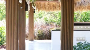 A covered outdoor area with wooden pillars, a thatched roof, and hanging greenery. - Welcome to Casa Hibiscus, your private tropical escape in Miami! 4-bd, 4-baths (Miami)