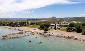 A coastal area with a beach, boats, and a building complex. - Sweetwater Links Lodge | Sleeps 20, Ideal Beach, Arcades, BBQ, Lake Views! (Garden City)