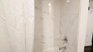 Une salle de bain avec une baignoire blanche, des carreaux de marbre et un rideau de douche.