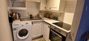 A compact kitchen with a washing machine, a dishwasher, and a stove. - Modern Central 1BDR At St Stephen Green (Dublin 2)