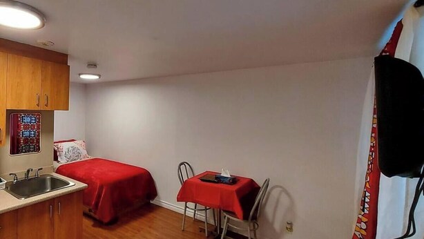 A small, compact room with a kitchenette, two single beds, a dining table, and a curtain. - #102 Enjoy your stay (Trois-Rivières)