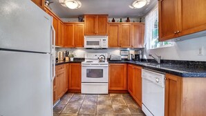 A kitchen with wooden cabinets, a white refrigerator, a stove, a microwave, and a sink.
