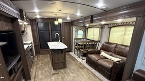 A compact RV interior with a kitchen, dining area, and seating space. - One bedroom RV next to OWA,restaurants, waterpark, and 15 minutes from beach. (Foley)