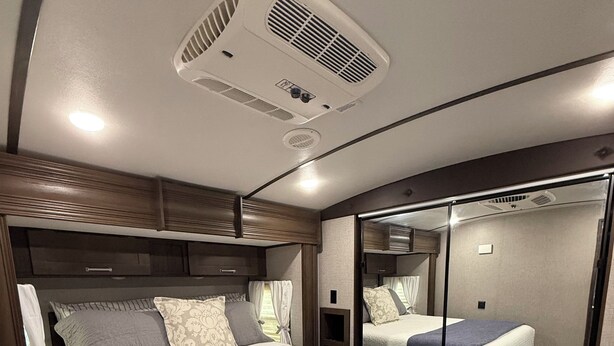 A bedroom with two beds, a large mirror, and a ceiling vent. - One bedroom RV next to OWA,restaurants, waterpark, and 15 minutes from beach. (Foley)