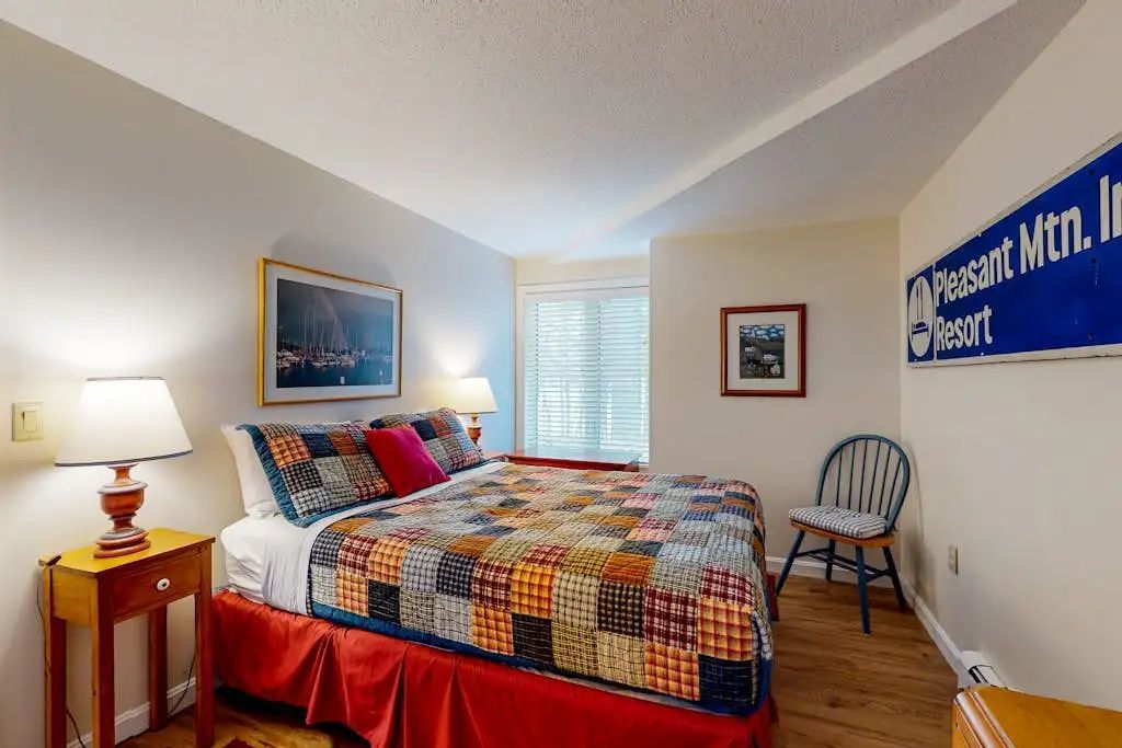 Une chambre à coucher avec un lit, une chaise, une lampe et un panneau décoratif sur le mur.