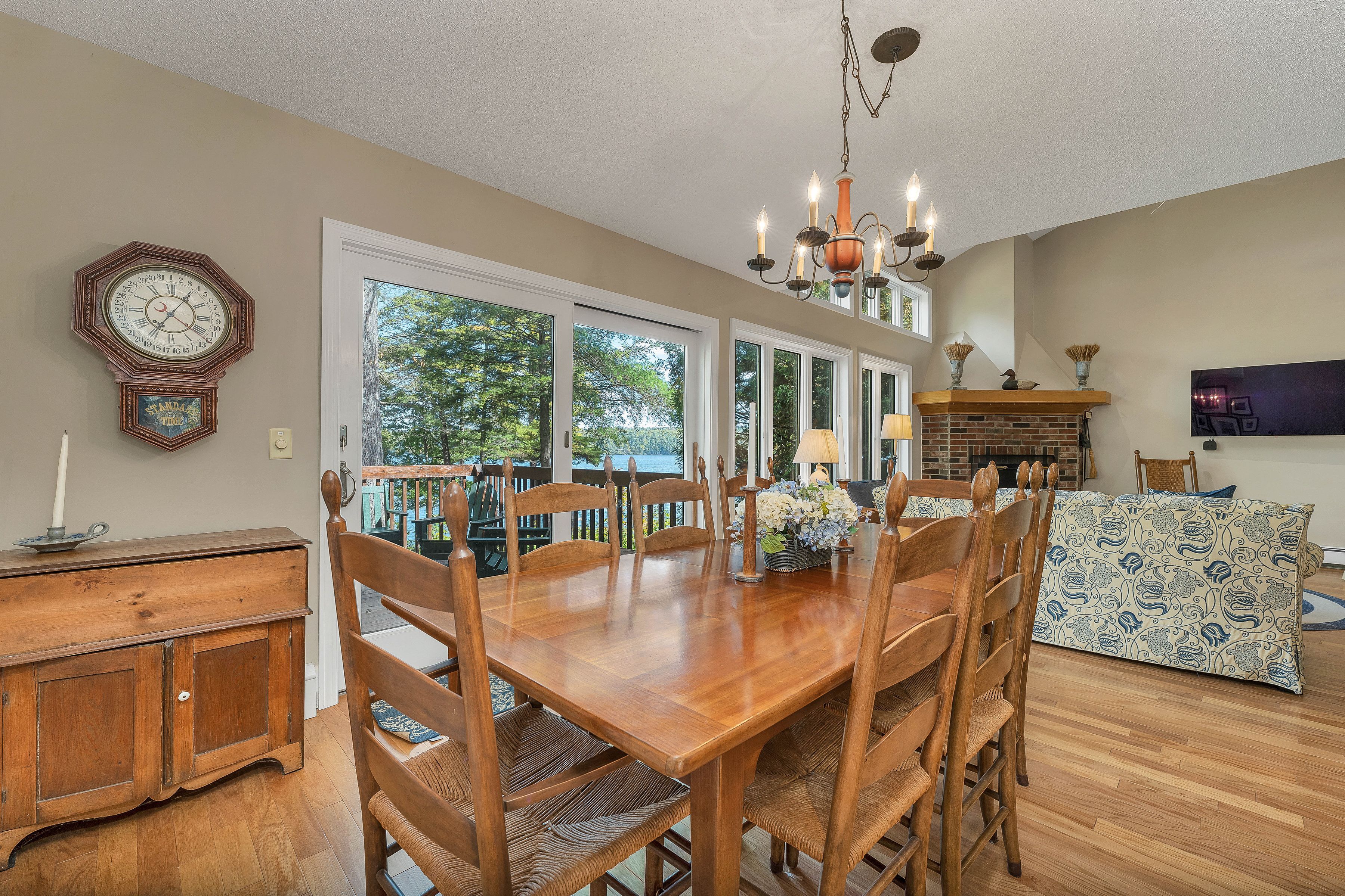 A dining area with a wooden table and chairs, a chandelier, and a view through the door.