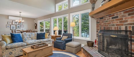 A spacious living room with a fireplace, large windows, and a variety of seating options.