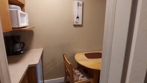 A small kitchen with a microwave, coffee maker, and a table with chairs. - #110 Enjoy your stay (Trois-Rivières)