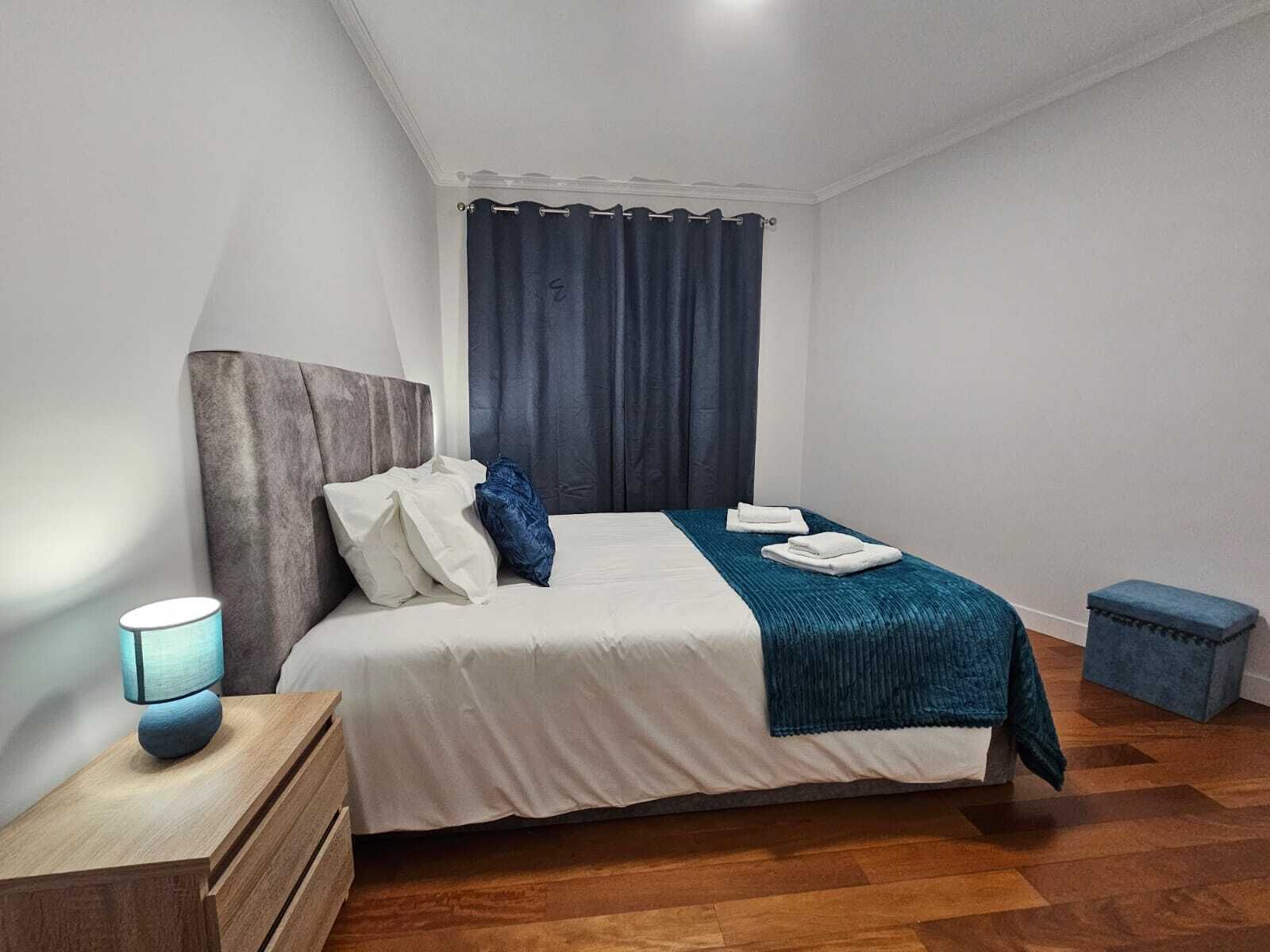 Une chambre à coucher bien rangée, avec un lit, une table de chevet et une petite table d’appoint.