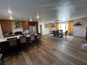 Cozinha espaçosa com armários de madeira, eletrodomésticos de aço inoxidável e uma ilha central com banquetas.