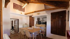 A rustic kitchen with a wooden table and chairs, a microwave, and a cabinet. - Apartment Sleeps 4 Alhama de Granada Town Centre (Alhama de Granada)