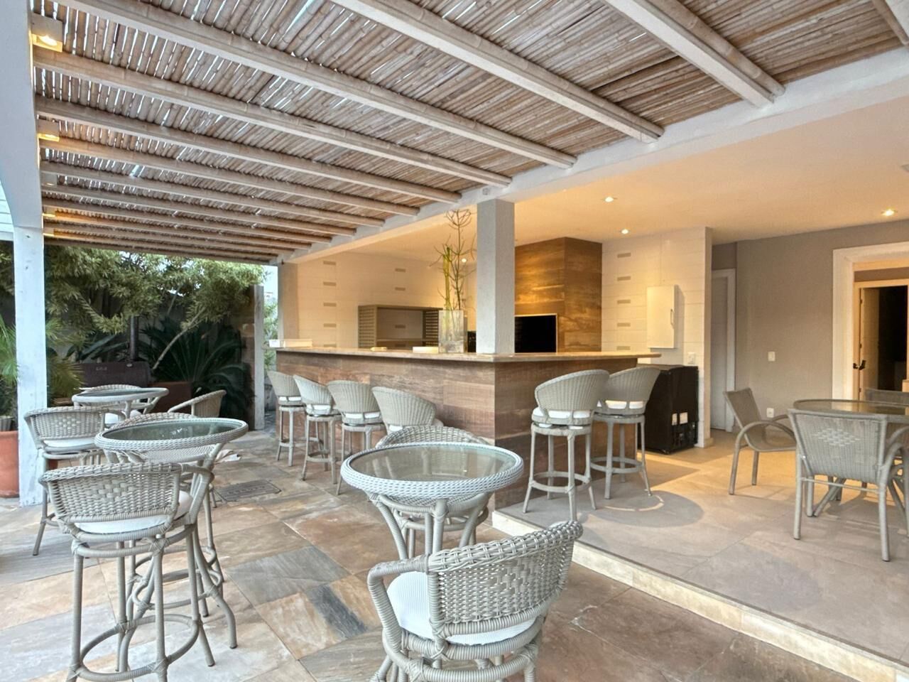 An outdoor patio area with wicker furniture, a bar, and a stone floor.