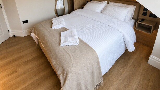 A modern bedroom with a large bed, wooden headboard, and a built-in wardrobe. - East Parade Collection, The Penthouse (North Yorkshire)