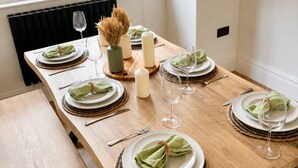 A dining table set with plates, glasses, and candles, with a view of a brick building outside. - East Parade Collection, The Penthouse (North Yorkshire)