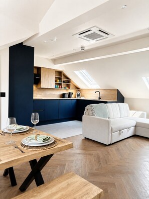 A modern loft apartment with a dining area, kitchen, and living space.