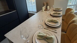 A modern dining area with a long table set for four, equipped with plates, glasses, and cutlery. - East Parade Collection, Opaz House Flat 2 (North Yorkshire)