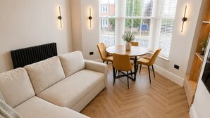 A modern living room with a sofa, a dining table with chairs, and a radiator. - East Parade Collection, 35 Nova House (North Yorkshire)