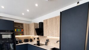 A modern kitchen with a built-in oven, a sink, and a black range hood. - East Parade Collection, 35 Nova House (North Yorkshire)