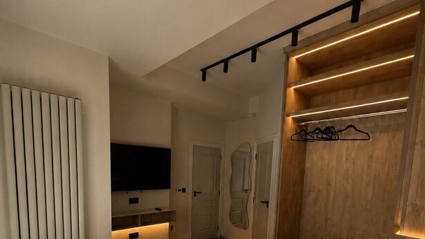 A modern bedroom with a large bed, wooden headboard, and built-in lighting. - East Parade Collection, 35 Nova House (North Yorkshire)