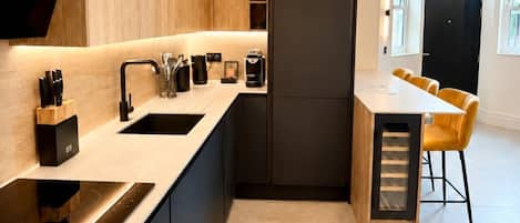 A modern kitchen with a built-in oven, a sink, and a dining area with a table and chairs.