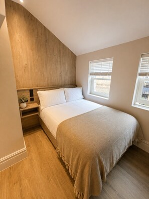 Une chambre à coucher avec un lit, des tables de chevet, une fenêtre et un mur d’accent en bois.