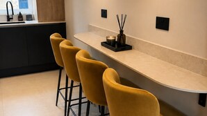 Cocina moderna con barra, que incluye una encimera amplia, cuatro taburetes y una ventana con vistas.