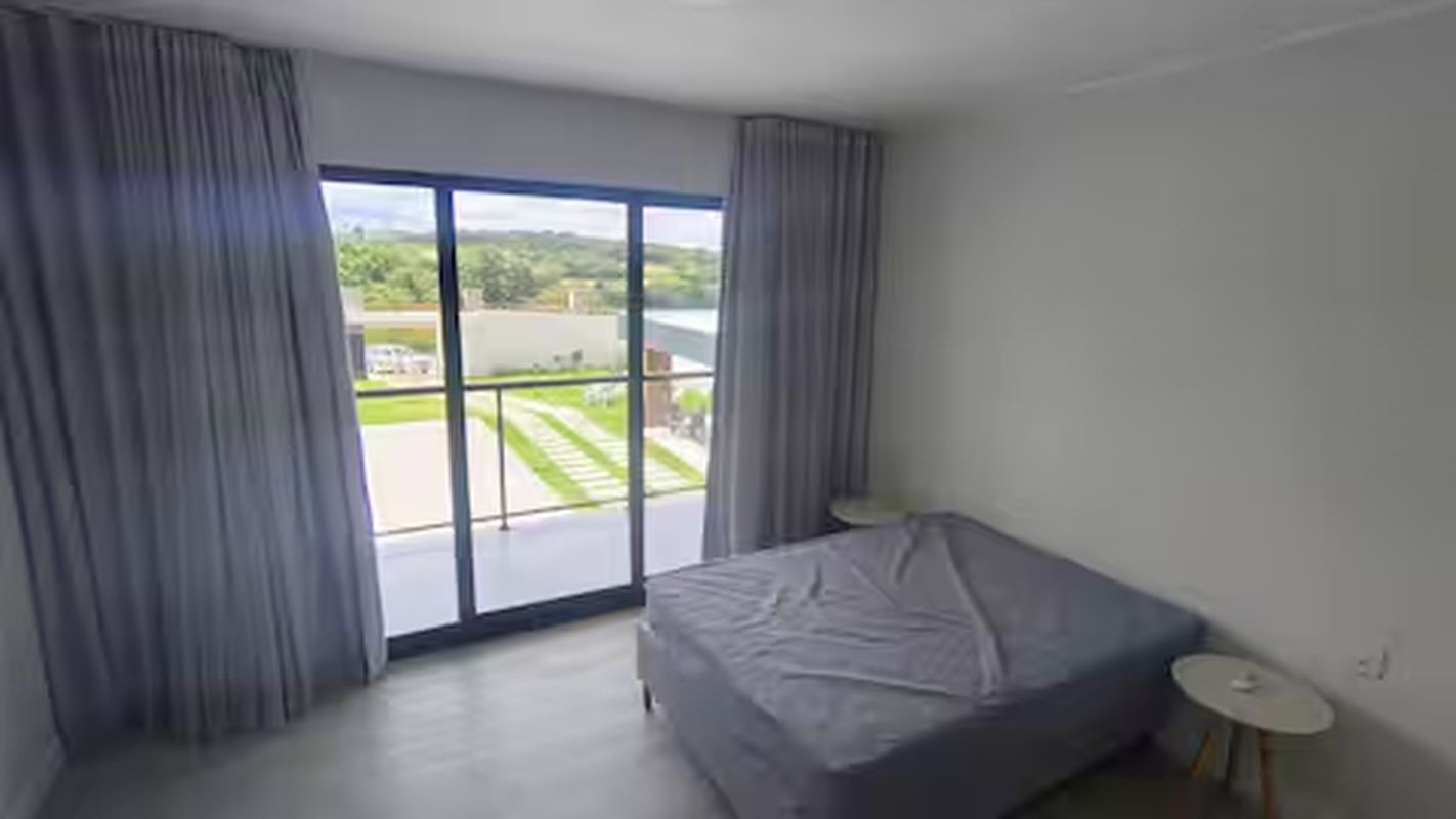 Ein Schlafzimmer mit großem Fenster, einem Bett und einem kleinen Nachttisch.