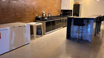 A modern kitchen with a wooden ceiling, a built-in oven, a sink, and a bar area with stools.