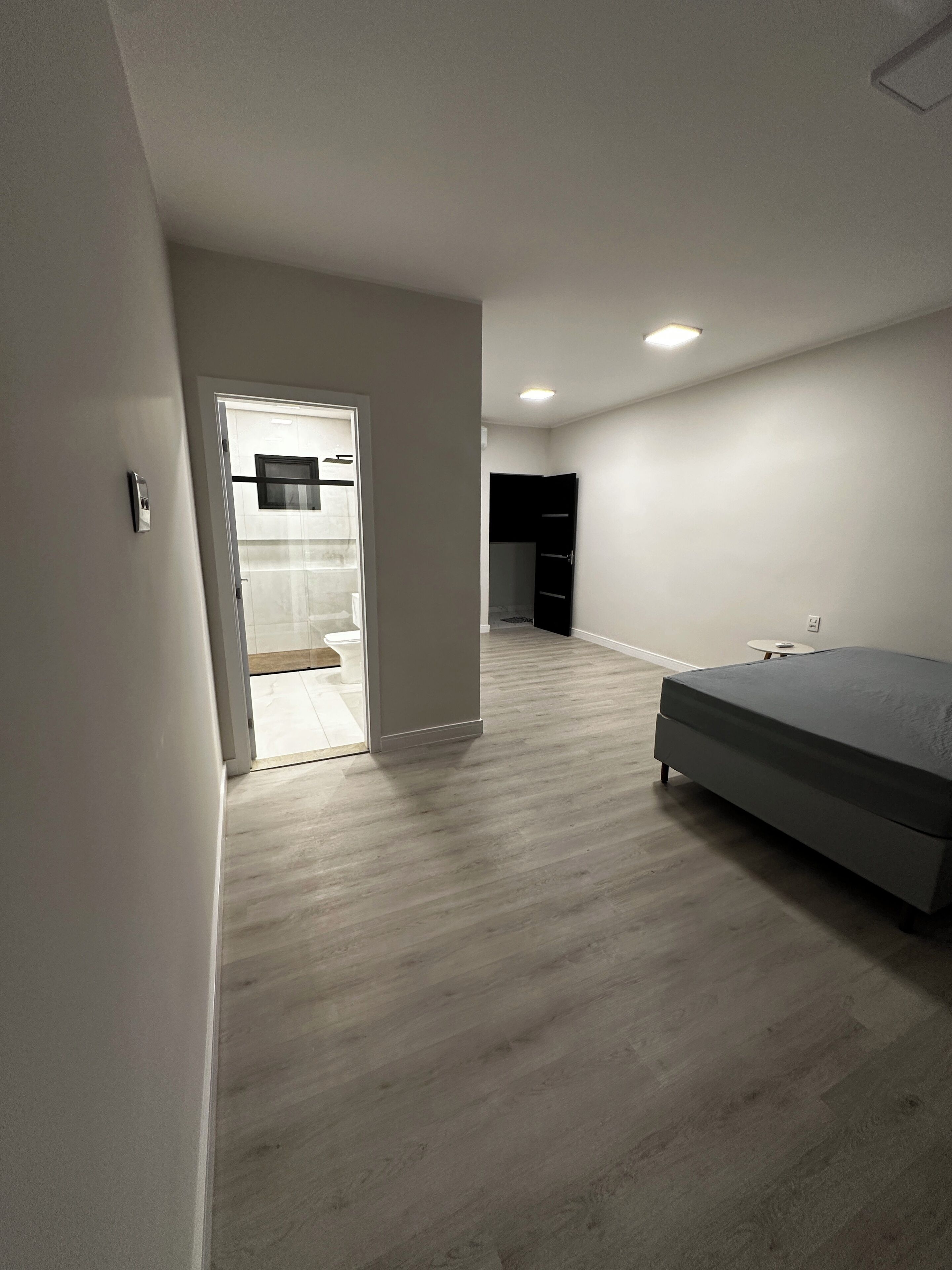 A modern bedroom with a bed, a wardrobe, and a door leading to a bathroom.