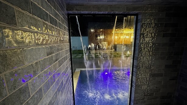 Un espace piscine intérieur moderne, agrémenté d’un élément aquatique et de murs éclairés.